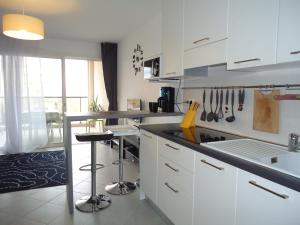 une cuisine avec des placards blancs et un comptoir dans l'établissement appartement, à Calvi