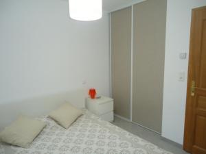 a white bedroom with a bed and a mirror at appartement in Calvi