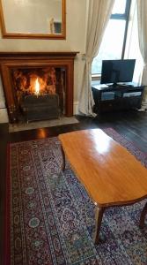 a living room with a fireplace and a coffee table at The Haven Cottage in Slamannan