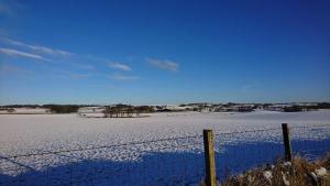 a fence in front of a snow covered field at The Haven Cottage in Slamannan