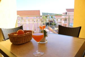 a table with a glass of orange juice and a basket of fruit at Apartments Marina in Vodice