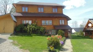 a large wooden house with flowers in the yard at ,, U Nikoli" in Bukowina Tatrzańska