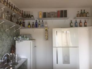 a kitchen with a refrigerator and shelves with bottles at Pousada Recanto Das Garças in Rio Preto Da Eva