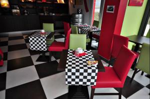 a restaurant with red chairs and tables and a checkered floor at Enzo Hotel Mulhouse Sud Morschwiller le Bas in Morschwiller-le-Bas