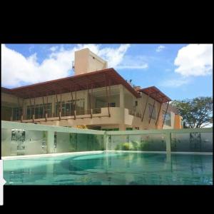 a large building with a swimming pool in front of it at Light and Chic - Tagaytay Vacation Pad in Tagaytay