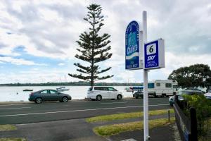 un estacionamiento con autos estacionados junto a un árbol en Bucklands Beach Waterfront Motel en Auckland