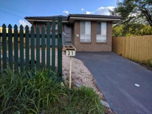 ein Haus mit einem grünen Zaun und einer Auffahrt in der Unterkunft Blue on McNab in Katoomba