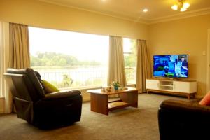 a living room with a large window and a television at Lake Domain Boarding Holiday House in Hamilton
