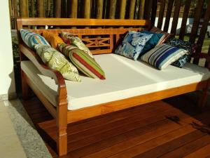 a wooden bench with pillows on it on a porch at Condomínio Solaris Imbassai in Imbassai