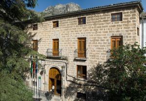 a large stone building with doors and windows and a mountain at Albergue Inturjoven Cazorla in Cazorla