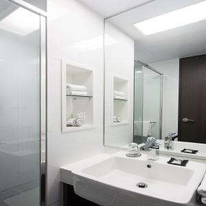 La salle de bains blanche est pourvue d'un lavabo et d'un miroir. dans l'établissement Urban Place Gangnam, à Séoul