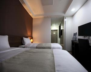a hotel room with two beds and a flat screen tv at Urban Place Gangnam in Seoul