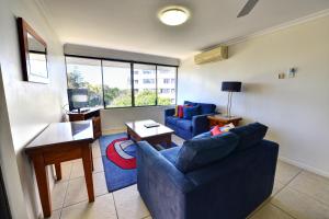 een woonkamer met een blauwe bank en een tafel bij Bellardoo Holiday Apartments in Mooloolaba