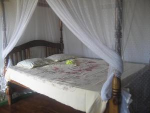 Schlafzimmer mit Himmelbett und weißen Vorhängen in der Unterkunft Fishermens Lodge & Restaurant in Ranna