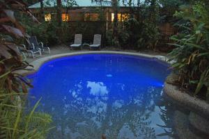 a large blue swimming pool with chairs in a yard at Heritage Lodge in Daintree
