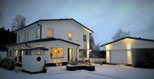a white house with a garage in the snow at Villa Jokivarsi Bed & Breakfast in Vantaa
