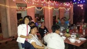 Eine Gruppe von Menschen, die auf einer Party am Tisch sitzen in der Unterkunft เฮือนปลายนา โฮมสเตย์ in Ban Sawan