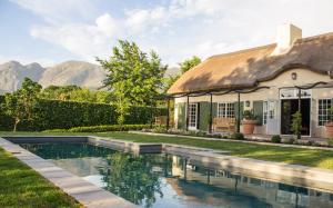 a house with a swimming pool in front of a house at La Clé Lodge in Franschhoek