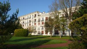 un grande edificio bianco con alberi di fronte di Le balcon de l'Hermitage a Le Touquet-Paris-Plage