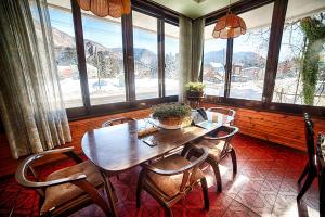 une salle à manger avec une table, des chaises et des fenêtres dans l'établissement Kagura Mitsumata Cottage, à Yuzawa