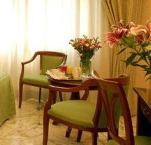 a table and two chairs with a vase of flowers on it at Hotel San Pietro in Rome