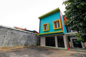 RedDoorz Plus near Halim Perdanakusuma 2 في جاكرتا: منزل ملون على جانب المبنى