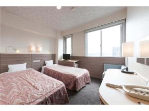 una camera d'albergo con due letti e una scrivania di Onomichi Daiichi Hotel a Onomichi