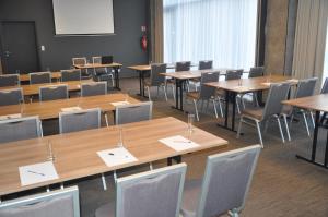 a classroom with wooden tables and chairs and a whiteboard at Ibis Poznan Polnoc in Suchy Las