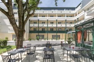 une cour vide avec des tables et des chaises devant un bâtiment dans l'établissement MÉDICIS HOME DIJON LES PETITES ROCHES, à Dijon