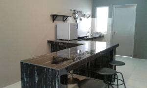 a kitchen with a counter with a sink and two stools at Gray Lodge in Port Dickson