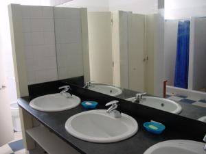 a bathroom with three sinks and a mirror at Stone Farm Hostel in Felgueiras