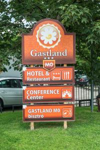 ein Schild für ein Hotelrestaurant im Gras in der Unterkunft Gastland M0 Hotel & Conference Center in Szigetszentmiklós