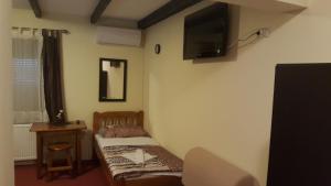 a small bedroom with a bed and a tv on the wall at Valpovački dvori B&B in Valpovo