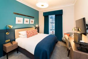 a bedroom with a bed, desk, and television at The Perle Oban Hotel & Spa in Oban