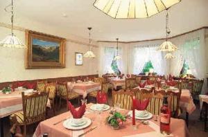 a dining room with tables and chairs with red decorations at Pension Villa Irene in Bad Harzburg