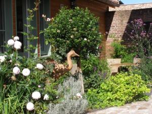 una estatua de un pato en un jardín de flores en Grange de la Herde en Camon