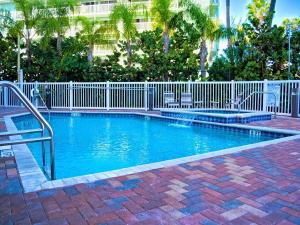 una piscina con una valla blanca y palmeras en Harborview Grande 802, en Clearwater Beach