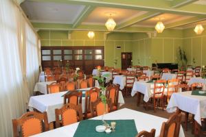 un comedor con mesas y sillas con manteles blancos en Hotel Hefaistos - Sovata, en Sovata