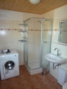 a bathroom with a shower and a sink and a washing machine at Haus Sturmschwalbe in Ummanz