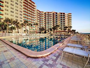 - une piscine avec des tables et des chaises à côté d'un bâtiment dans l'établissement Regatta Beach Club C713, à Clearwater Beach