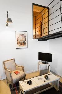 - un salon avec une table, une télévision et une chaise dans l'établissement Surprenantes- Jules Verne, à Nantes