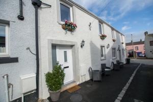 a row of white buildings with flower pots on them at Red Rose Cottage in Cockermouth