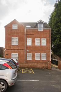 a brick building with a car parked in front of it at Crosshills Serviced Apartments in Leeds