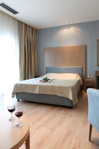 a bedroom with a bed and two glasses of wine at Hotel Alfa in Edessa