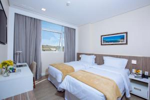 a hotel room with two beds and a window at Intercity Suape Costa Dourada in Cabo de Santo Agostinho +16 photos