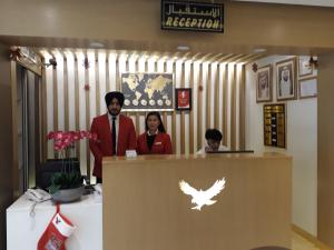 un hombre y una mujer parados detrás de un mostrador en una tienda en Royal Falcon Hotel, en Dubái