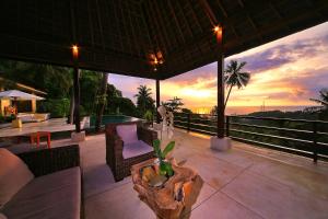 un patio con mesa, sillas y puesta de sol en Villa Marley en Senggigi 