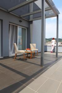 a woman standing on a balcony with a table and chairs at Hotel Alfa in Edessa