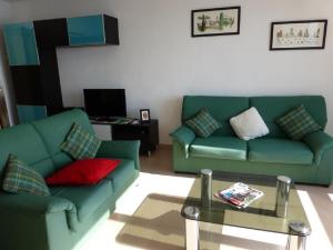 Sala de estar con 2 sofás verdes y mesa de centro en Apartment La Rosa (Blaumar), en Sant Andreu de Llavaneres