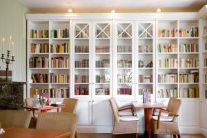 ein Zimmer mit weißen Bücherregalen voller Bücher in der Unterkunft Cafe´Seestrasse in Magdeburg